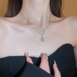 Close-up of elegant gold water drop pendant necklace with sparkling rhinestones on model
