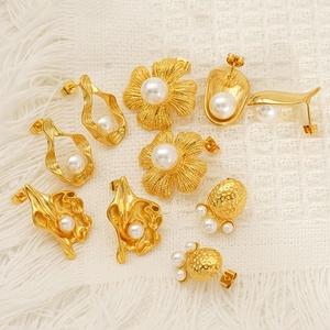 Elegant gold titanium steel floral earrings with pearls displayed on soft fabric