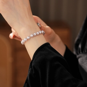 Close-up of lavender pearl bracelet on wrist with elegant velvet sleeve background