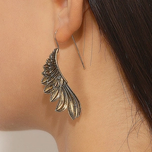 Detailed view of vintage gold hollow wing earrings worn on model for stylish look