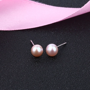 Macro detail of natural pink freshwater pearl stud earrings with elegant silk ribbon