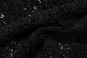 Macro shot of black floral lace fabric with intricate crochet patterns and mesh structure