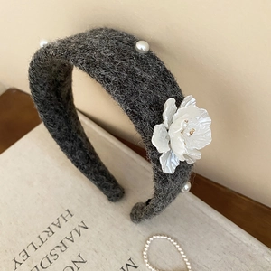 Detailed texture of gray velvet headband with white resin flower and pearl embellishments