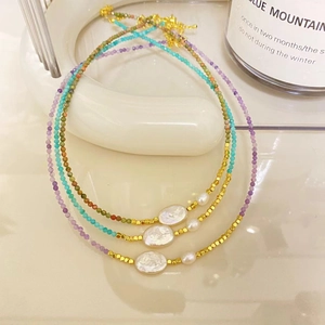 Close-up of tourmaline and baroque pearl beaded necklaces in pink, blue and green colors