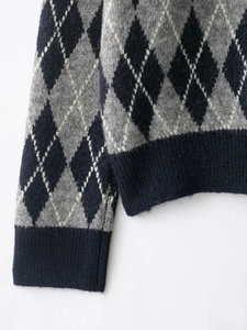 Detail of argyle knit sweater showing grey and white diamond pattern with ribbed cuffs