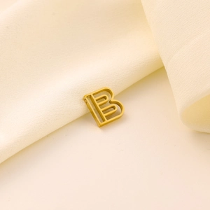 Vue détaillée du pendentif lettre B dorée sur fond élégant en tissu de soie beige