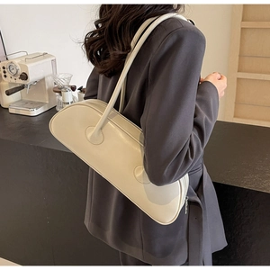 Model wearing a large white leather underarm bag with minimalist shoulder strap design