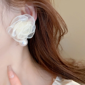 Close-up of elegant oversized lace flower earrings with pearl drop on model