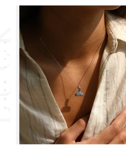 Artistic close-up of a silver mermaid tail necklace with blue gradient crystals on a model