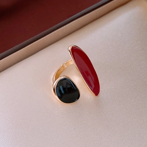 Detailed shot of open ring featuring red and black enamel ends on a satin background
