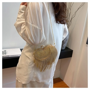Detail of golden heart-shaped evening bag with shimmering rhinestones and long fringe