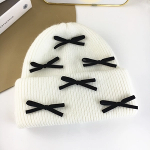Detail view of cream knit beanie with six black velvet bows and soft rabbit fur texture