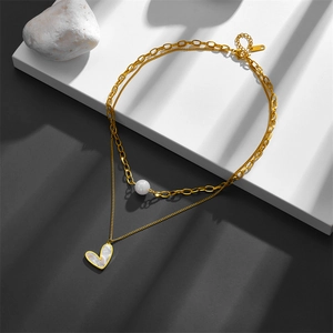 Detailed macro view of gold-layered stainless steel necklace with pearl and heart pendant