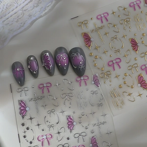Macro shot of 5D gel bow and star nail stickers with 3D metallic texture on falsenails
