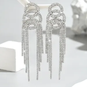 Close-up of silver long tassel earrings with sparkling rhinestones on grey background