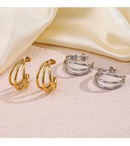 Detail view of triple-layered C-shaped hoop earrings in polished gold and silver steel