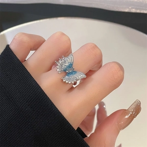 Macro shot of silver butterfly ring with translucent blue wings and zircon inlay on hand