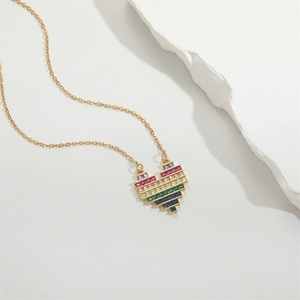 Rainbow heart pendant necklace with gold chain on white textured stone display