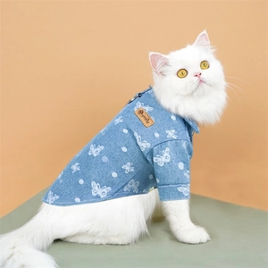 Detail of blue denim pet shirt with white butterfly patterns and a small leather smile tag
