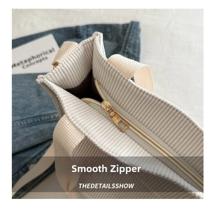 Detailed macro view of smooth golden metal zipper and corduroy texture on tote bag