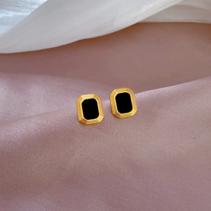 Detail of square titanium steel earrings with black inlay on pink and white silk