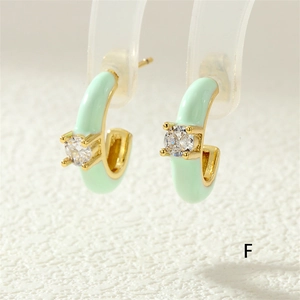 Close-up of mint green enamel C-shaped earring with gold base and zircon inlay