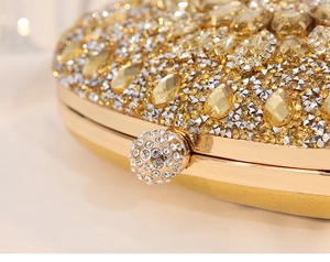 Detailaufnahme einer goldenen Luxus-Abendtasche mit glitzernden Strasssteinen und Verschluss.