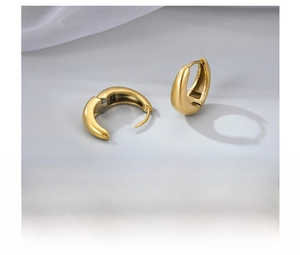 Macro detail of gold vacuum-plated titanium steel hoop earrings with glossy finish
