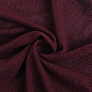 Détail macro du tissu mesh bordeaux avec texture respirante et plis drapés élégants