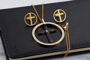 Macro view of gold stainless steel cross necklace set with tortoise resin and diamonds