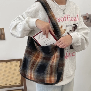 Detail shot of the large capacity wool plaid hobo bag holding a standard book