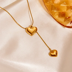 Elegant gold double heart pendant necklace with snake chain on silk background
