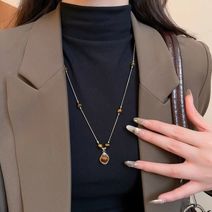Detail of vintage flower tiger eye stone pendant on golden beaded chain necklace