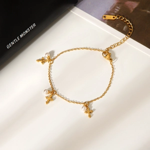 Elegant gold cross bracelet with white pearls and K18 hallmark on a white surface