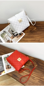 Close-up of quilted bucket bags in white and red with gold metal locks on wooden desk