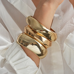 Detail showing a stack of three chunky gold polished bangles with organic geometric shapes
