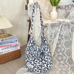 Detail of white fabric shoulder bag featuring elegant blue butterfly prints and ties