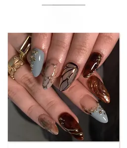 Macro detail of almond press-on nails featuring marble texture and gold metallic accents