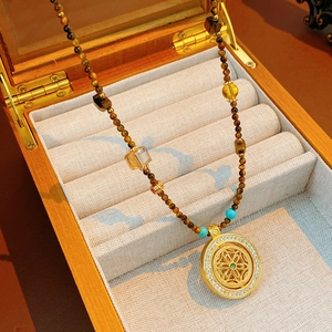 Detail of tiger eye bead necklace with golden镂空pendant on elegant jewelry box