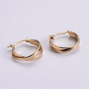 Macro detail of gold-plated hoop earrings featuring a unique double-layer twisted design