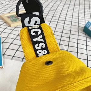 Detail of yellow canvas chest bag featuring letter print webbing and metal eyelet