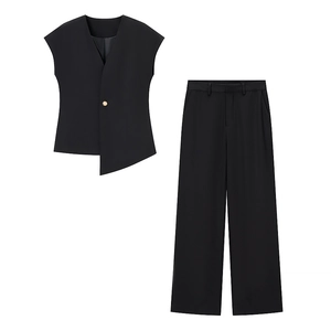Detail of black asymmetric vest with gold button and matching wide-leg trousers set