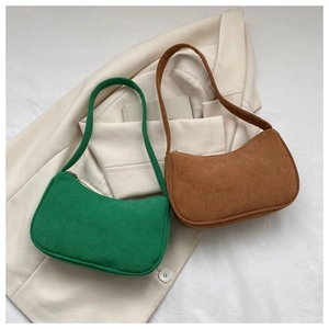 Flat lay of green and brown corduroy baguette underarm bags on a beige blazer background
