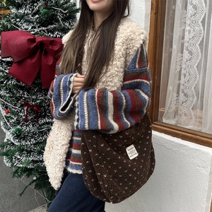 Close-up of brown plush heart crossbody bag with polka dots and signature brand label
