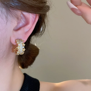 Close-up of a gold-plated C-shaped earring with zircon micro-pave setting on a model