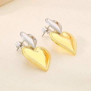 Détail des boucles d'oreilles cœurs superposés bicolores or et argent avec fini miroir