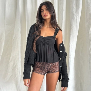 Detail of three-piece set featuring black knitted cardigan and leopard print shorts