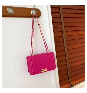 Detail view of hot pink quilted crossbody bag featuring a golden metal twist lock and chain