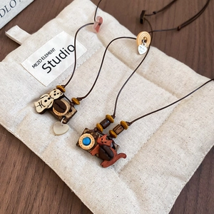 Close-up of handmade wooden bear and cat pendants with resin beads on brown wax cord