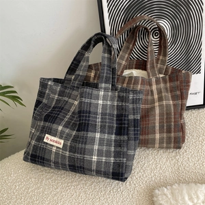 Detail of vintage plaid fabric texture and woven logo tag on large tote handbag